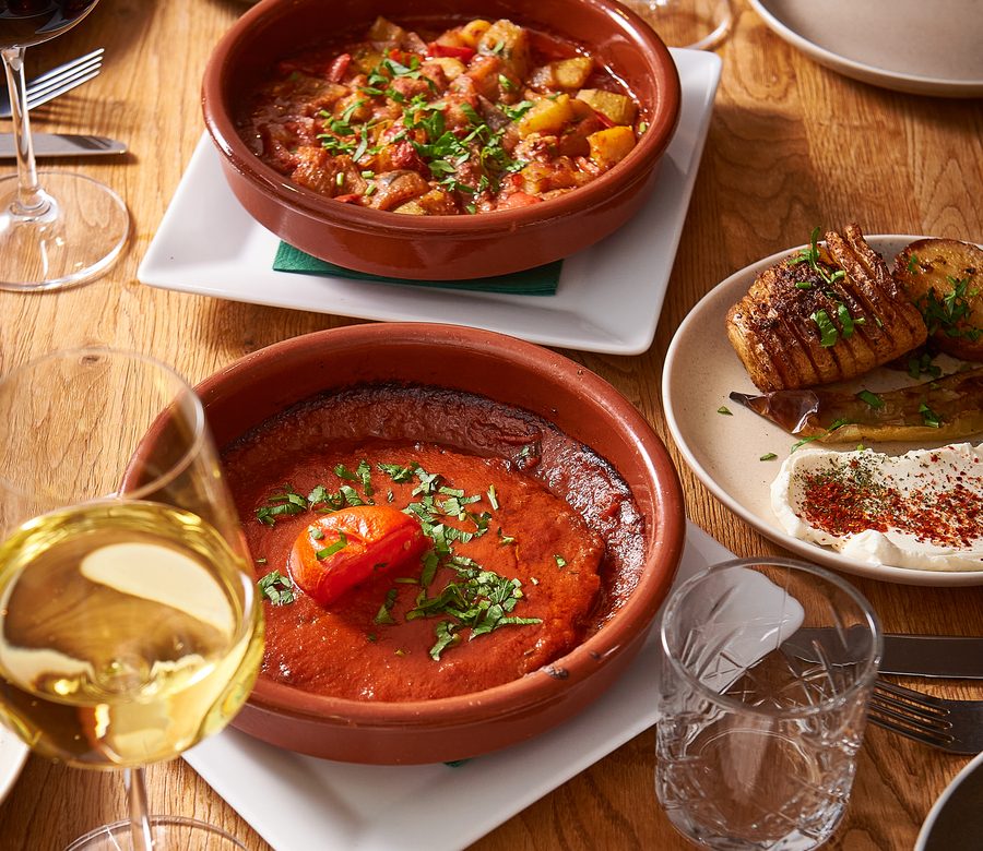 Gedeckter Tisch mit Güveç im Tontopf, Tepside Et und Ofenkartoffeln